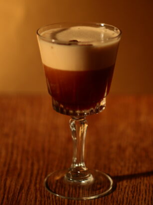 Espresso Martini in a stemmed cocktail glass with a thick foam layer and three coffee beans on top