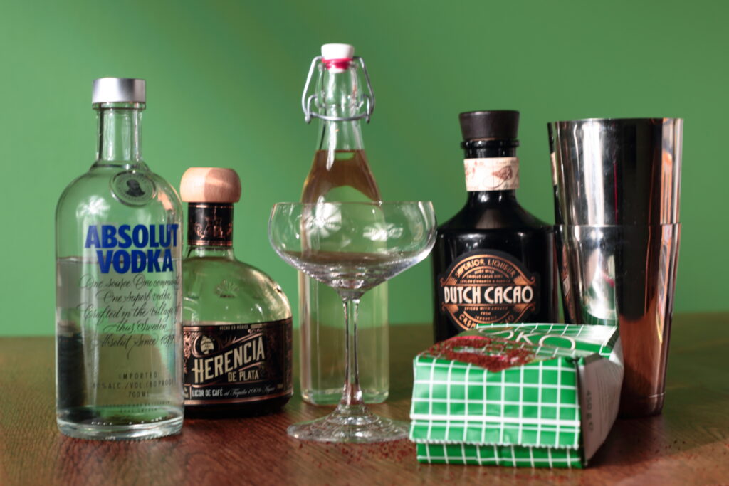 Espresso Martini ingredients including vodka, Herencia coffee liqueur, Dutch cacao, fresh espresso, and sugar syrup with a cocktail shaker