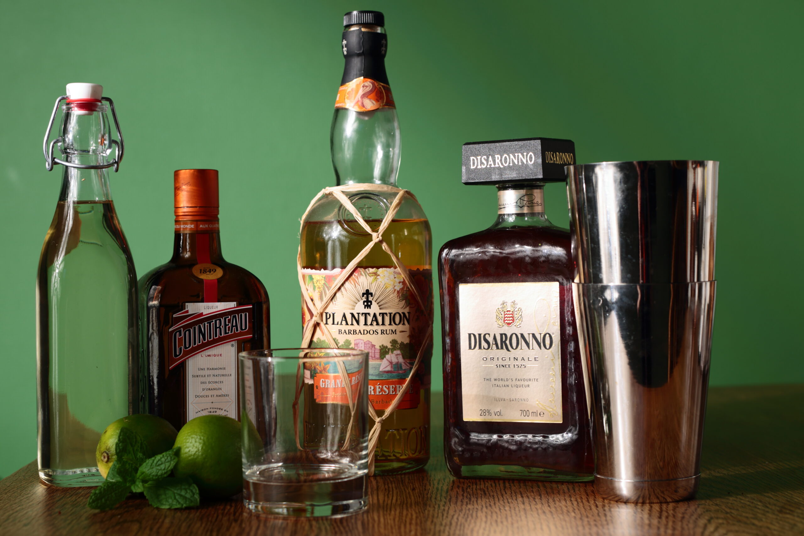 Amaretto Mai Tai ingredients including Plantation rum Cointreau Disaronno lime and cocktail shaker with rocks glass